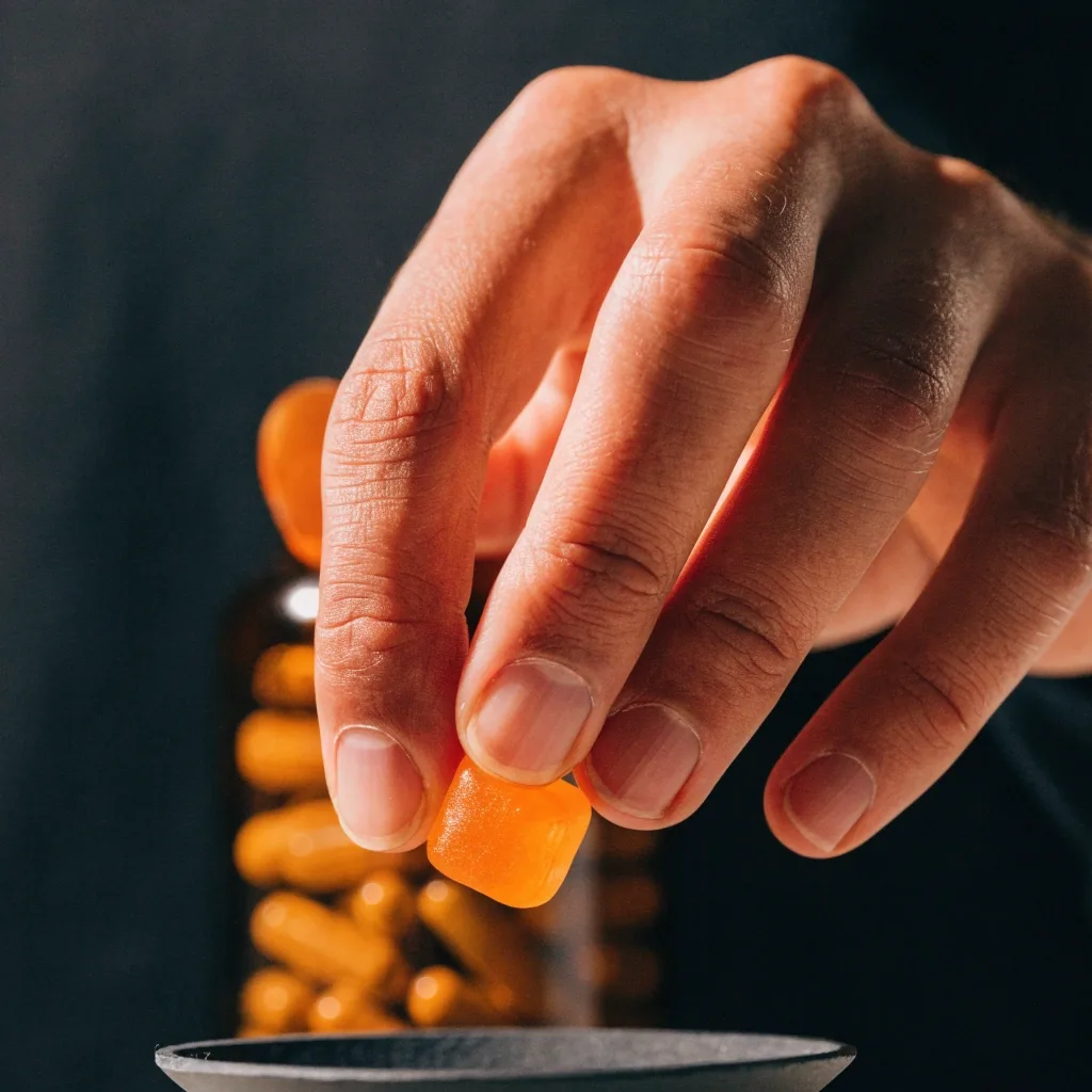 Soft chew gummy cube on dark slate under amber practical light